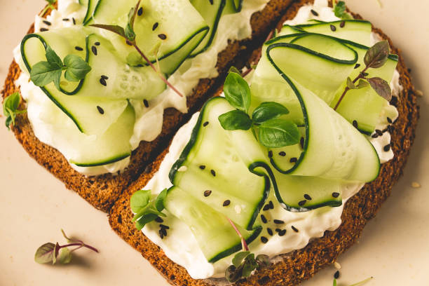 istock Breakfast, cereal bread sandwiches, cream cheese, sliced cucumber, with micro greenery on a light table, close-up, top view, selective focus, no people, 1405854171