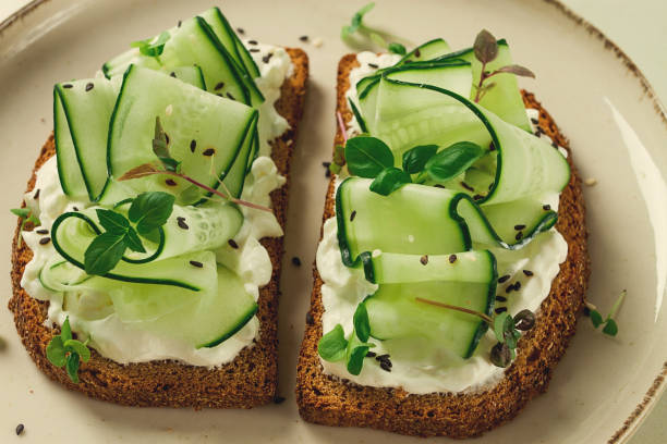 istock Breakfast, cereal bread sandwiches, cream cheese, sliced cucumber, with micro greenery on a light table, close-up, top view, selective focus, no people, 1405854371