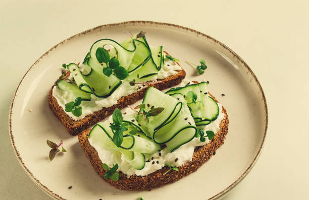 istock Breakfast, cereal bread sandwiches, cream cheese, sliced cucumber, with micro greenery on a light table, close-up, top view, selective focus, no people, 1405854372