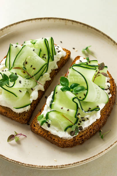 istock Breakfast, cereal bread sandwiches, cream cheese, sliced cucumber, with micro greenery on a light table, close-up, top view, selective focus, no people, 1405854373