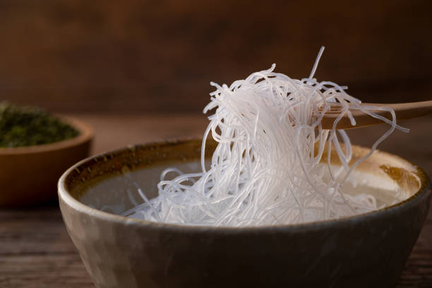 nahaufnahme fresh glass noodle (transparente bohnenfadennudeln) auf holzgabel - mung bean stock-fotos und bilder