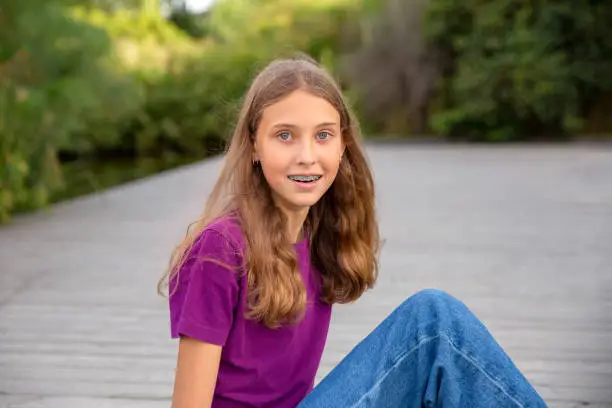 Young girl portrait in the park with natural light. wearing a purple tee.