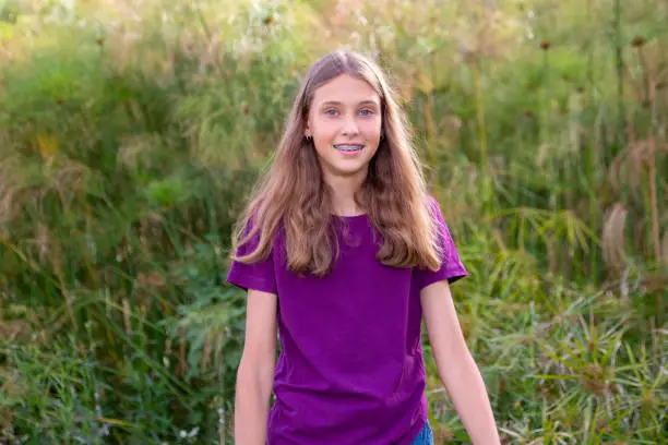 Young girl portrait in the park with natural light. wearing a purple tee.
