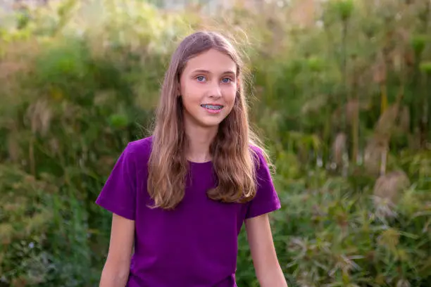 Young girl portrait in the park with natural light. wearing a purple tee.