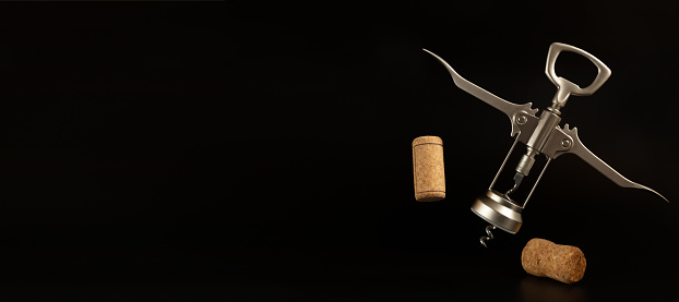 Wine corkscrew and cork stopper on the black background with copy space.