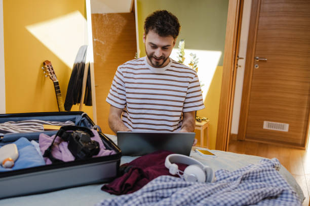 istock Front view of young happy man making online reservation and preparing for a vacation 1405857895