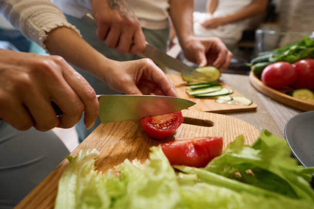 istock Person cutting tomatoes on chopping board near lettuce 1405862039