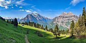 istock Fantastic morning mood in the mountains of glarus. Sun on the alp. View of an alpine hut in front of the big mountian 1405862444