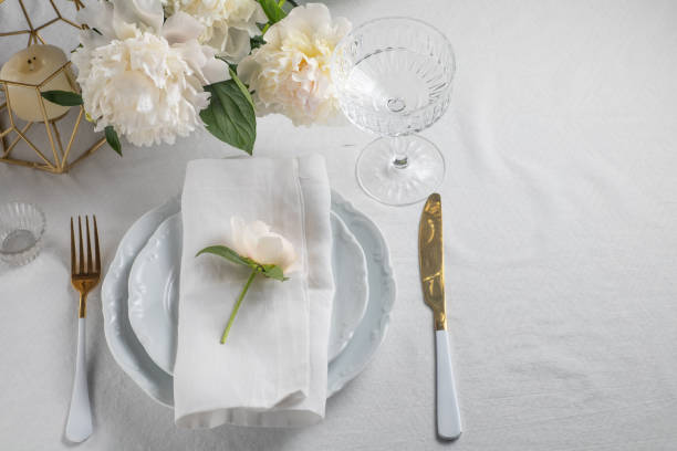istock romance table setting with peony flowers on white tablecloth with golden cutlery. Copy space 1405862559
