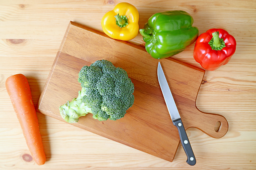Top View of a Fresh Broccoli on Cutting Board with Knife and Another Vegetables Scattered Around