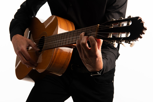 Isolated classical guitar and guitarist's hands playing a chord shape up close on a white background with copy space