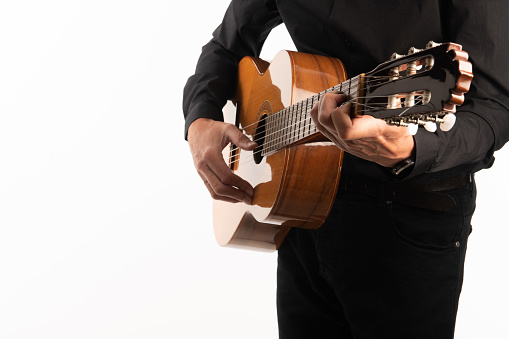 Isolated classical guitar and guitarist's hands playing a chord shape up close on a white background with copy space