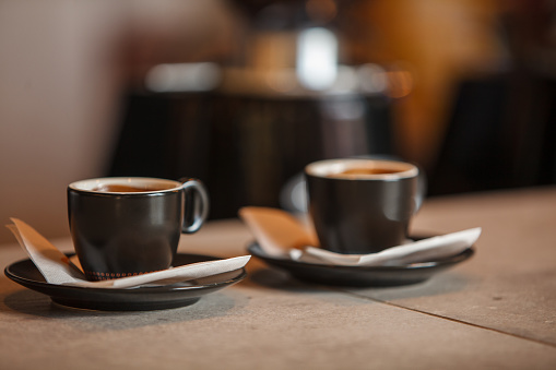 Close up shot of two cups of freshly brewed espresso coffees served on a bar counter.