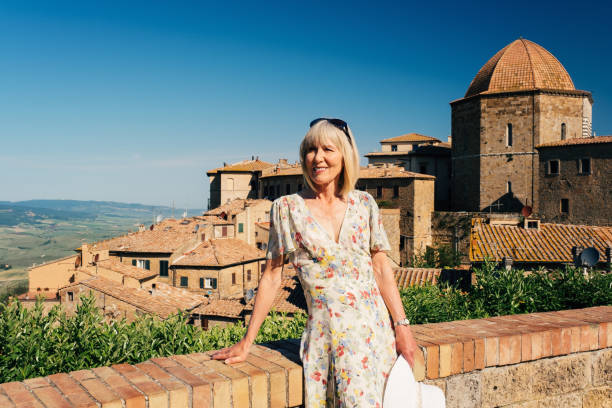 Mature woman on vacation enjoying the view from the village of Volterra in the Tuscany region of Italy.