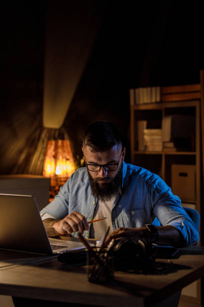 istock Young man looking at his project notes and brainstorming ideas when working late 1405870254