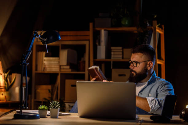 istock Hipster businessman working late at his desk, reading project notes he wrote 1405870259