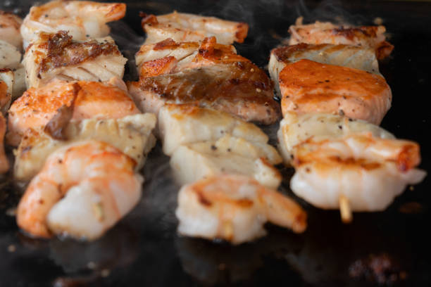 istock Shrimps and salmon cooking on black barbecue background 1405871459