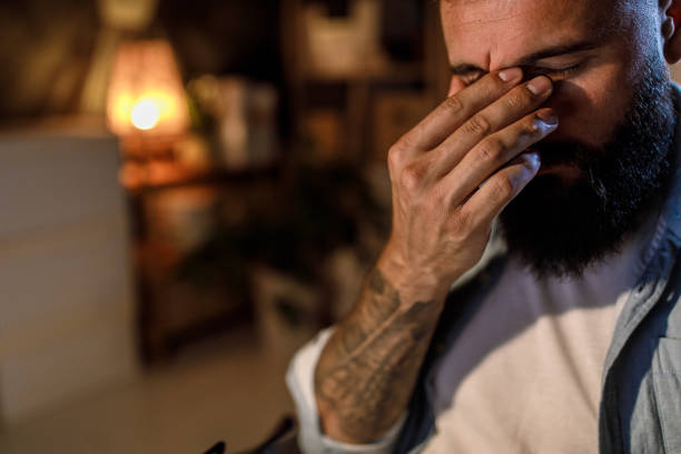 istock Overworked young man rubbing his eyes when working late at the office 1405871666