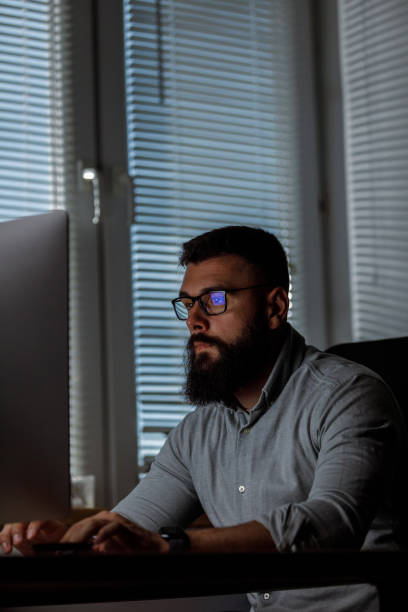istock Serious young businessman sitting at desk in his small office and typing data on computer 1405873721