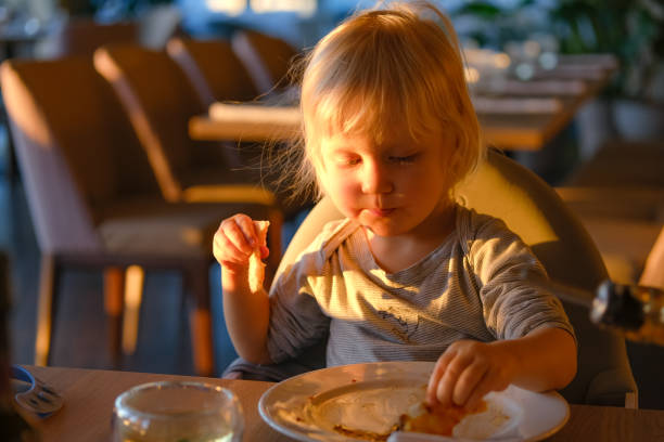 istock Little blond child eating pizza in restaurant. 1405873795
