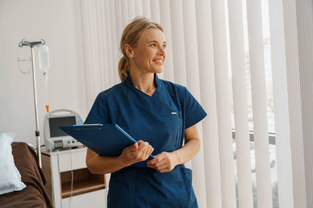 Professional nurse with tablet standing in hospital ward and looking window Professional nurse with tablet standing in hospital ward and looking window. High quality photo doctors bag stock pictures, royalty-free photos & images