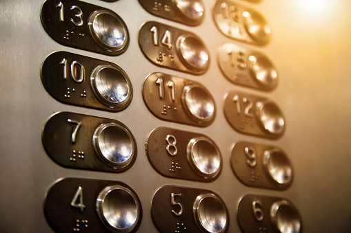 Close-up background of buttons on an elevator panel with button for visually impaired in skyscraper. Inside modern metal elevator houses floor selection buttons with sunlight. Copy space