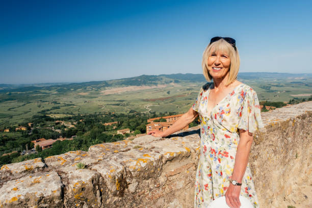 Mature woman on vacation enjoying the view from the village of Volterra in the Tuscany region of Italy.
