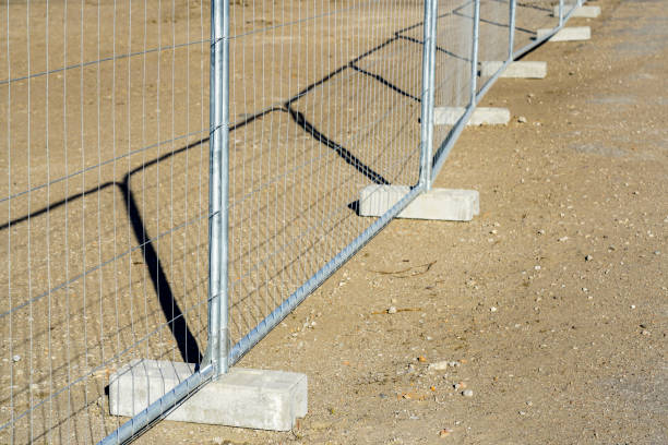 Temporary metallic portable fence with concrete base blocks to limit the territory Temporary metal portable fence with concrete base blocks with holes for delimiting different areas temporary stock pictures, royalty-free photos & images