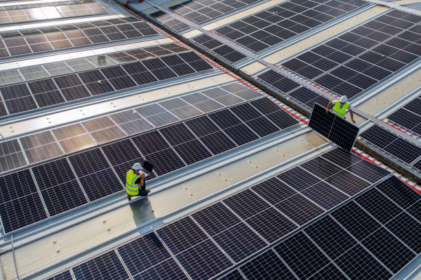 istock Team of engineers using technology while installing solar pamels on a roof of warehouse. 1405880245