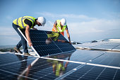 Zwei Ingenieure, die Sonnenkollektoren auf dem Dach installieren.