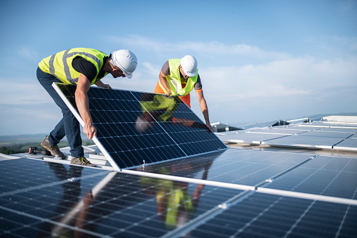 Dos ingenieros instalando paneles solares en el techo. photo