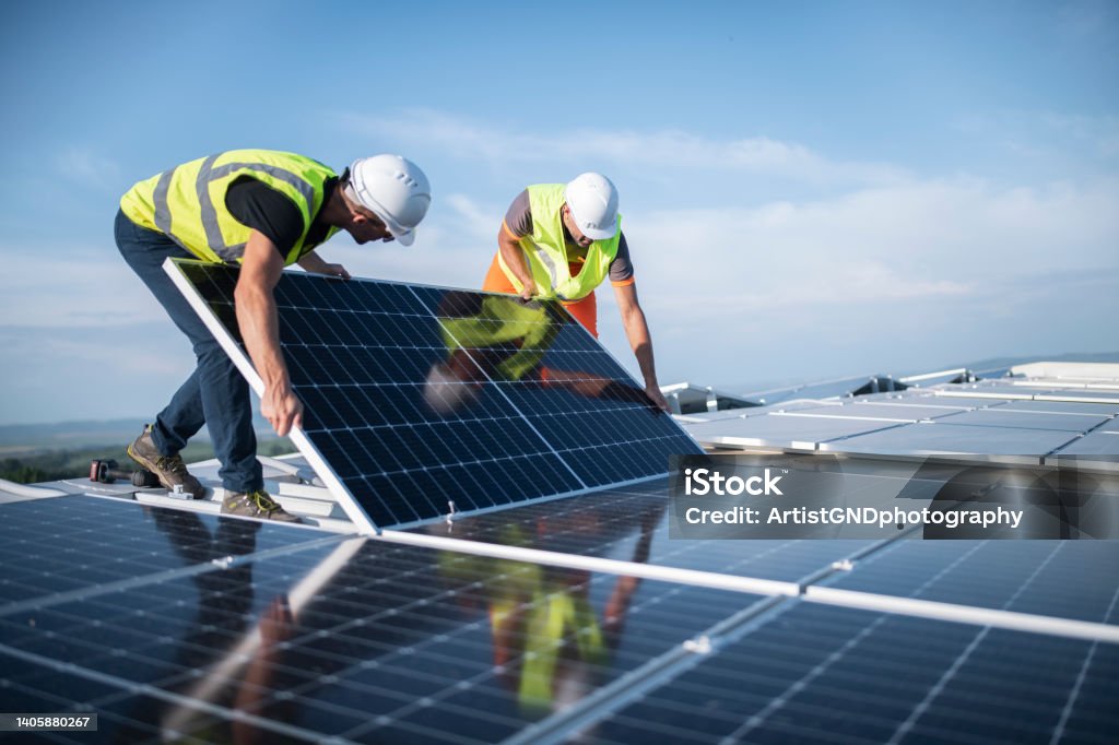 Two engineers installing solar panels on roof. Team of two engineers installing solar panels on roof. Solar Panel Stock Photo