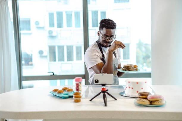 bel uomo afroamericano che cucina e registra un video - muffin blueberry muffin blueberry food foto e immagini stock