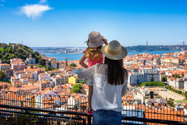 A tourist mother and her little daughter enjoy the view of the beautiful cityscape of Lisbon A tourist mother and her little daughter enjoy the view of the beautiful cityscape of Lisbon, with the colorful houses and roofs, Portugal baixa stock pictures, royalty-free photos & images