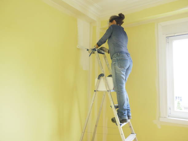 istock Woman painting a yellow wall white 1405883310
