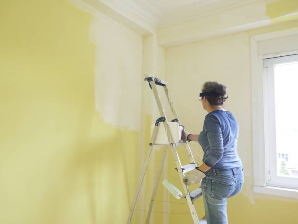 istock Woman painting a yellow wall white 1405883313
