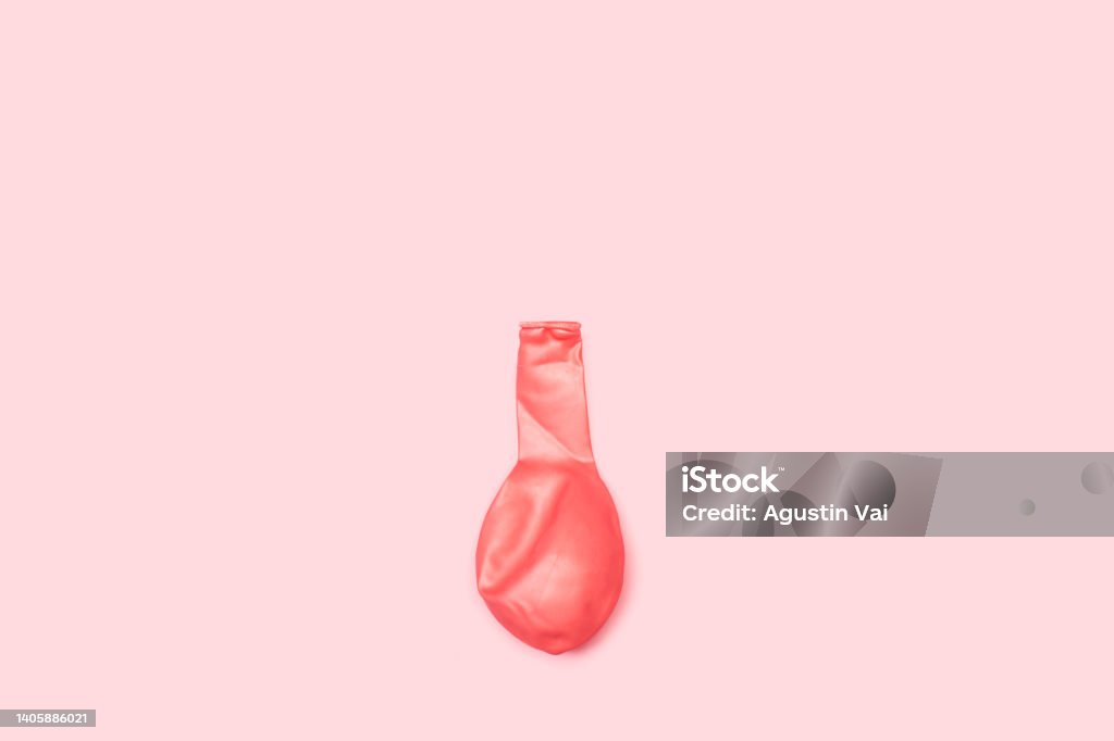 A deflated pink balloon on a pink background A deflated pink balloon on a pink background with copy space Balloon Stock Photo