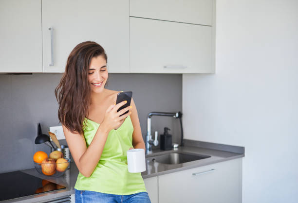 istock Beautiful smiling woman is using smart phone on the kitchen at home. 1405887636