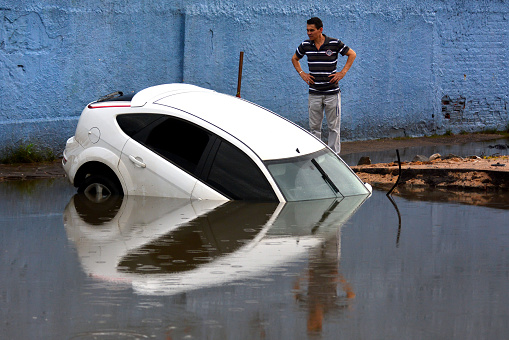 Porto Alegre, Rio Grande do Sul, Brazil - Oct 15th, 2015: Man looking at a white car flooded