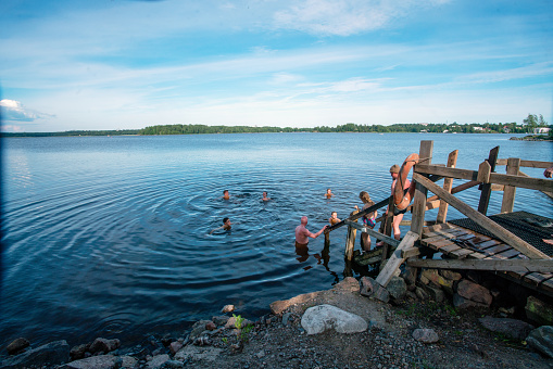 06-22-2022  Helsinki , Finland. People swimming  in lake after sauna -  fantastic summer  ( weekday in Helsinki) Healthy lifestyle!