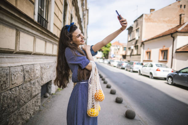 istock Young woman using mobile phone and carrying shopping bag 1405890449