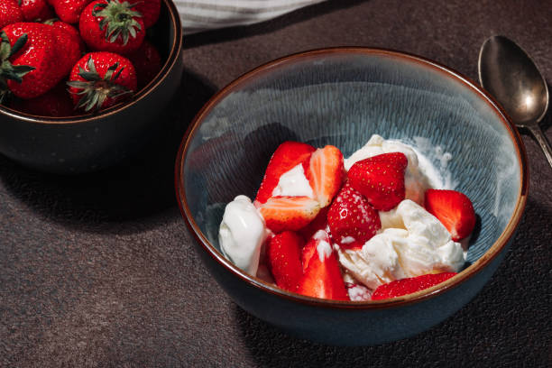 istock Vanilla ice cream with strawberry pieces in a deep blue bowl on a brown background 1405893581