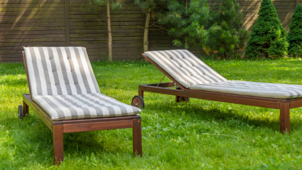 istock Lounge chairs on the backyard in a beautiful garden. Two empty sunbeds on the grass. 1405893821