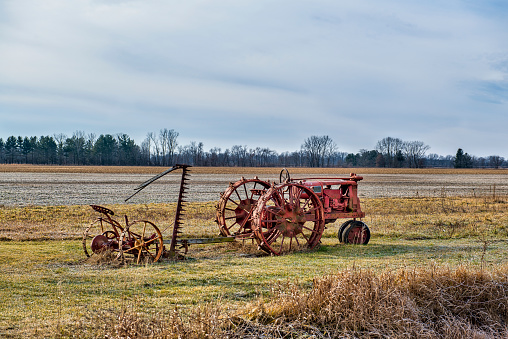 Old Tractor and Mower sit abandon in rural farm field.