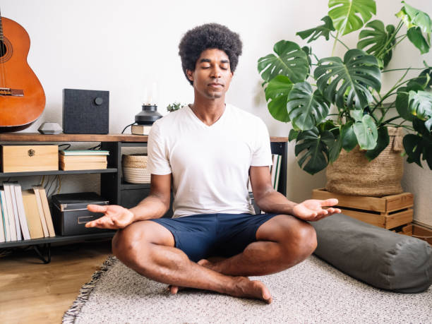 istock Afro man meditating or practicing yoga in an apartment or at home 1405896178
