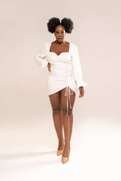Fashionable elegant african woman wearing white mini dress, looking at the camera. Full length photo. Studio background. Copy space.