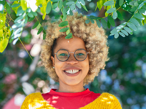African American woman with afro hair and glasses among the greenery