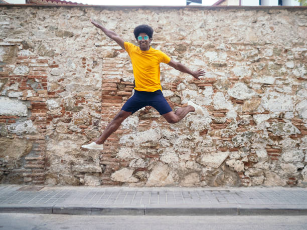 istock Smiling afro man jumping for joy on the street 1405896972