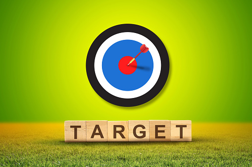 Target board with arrows on yellow background, target on word letters cube, success concept