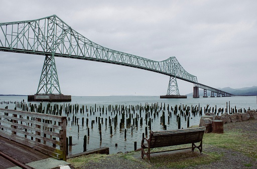 A vintage style photo of a bench overlooking the Columbia River. Taken in Astoria, Oregon.